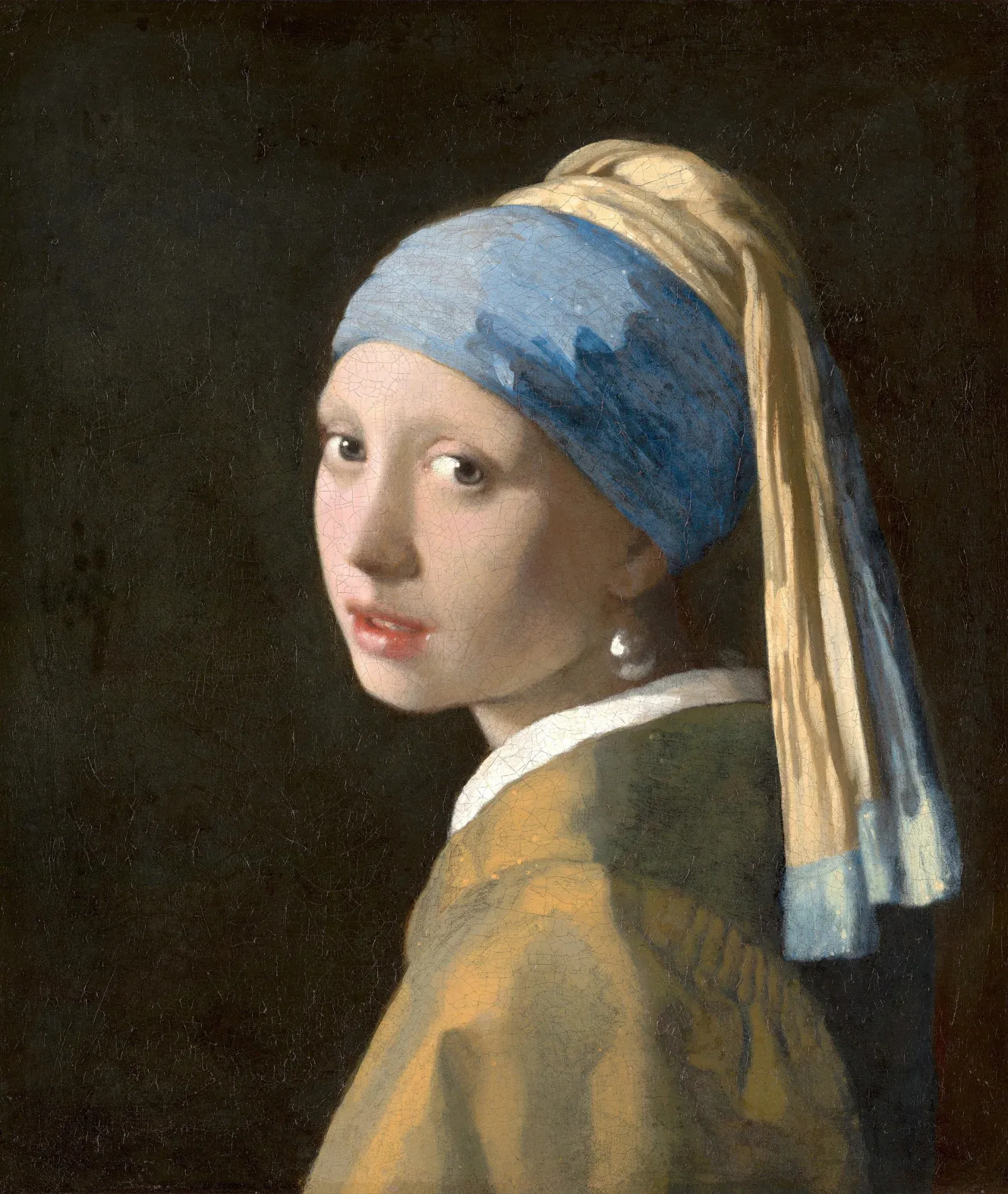 A young woman in a blue and yellow turban looks back over her shoulder against a dark background, lips parted, a large pearl earring catching the light.